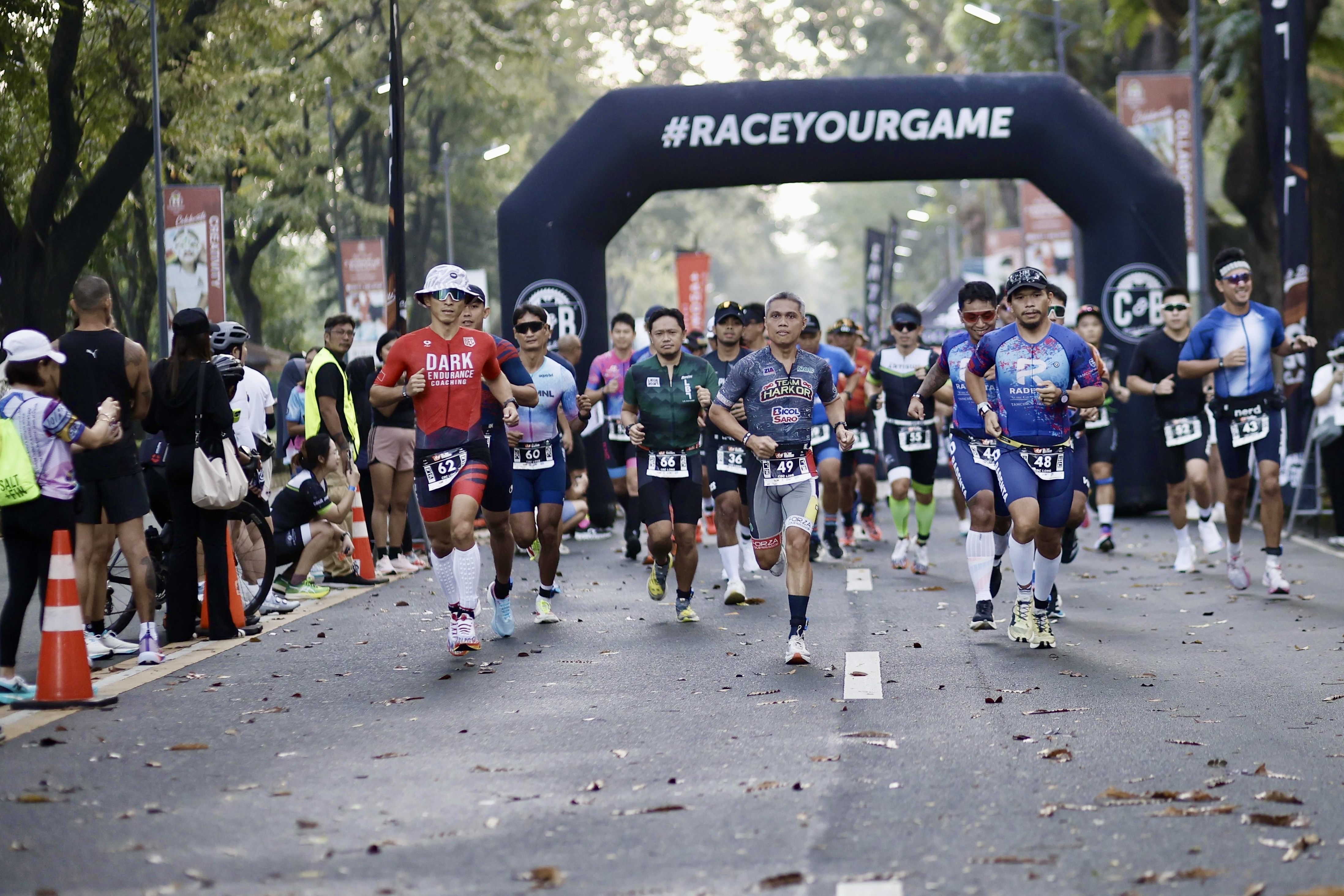 Athletes at the run start under a #RACEYOURGAME arch